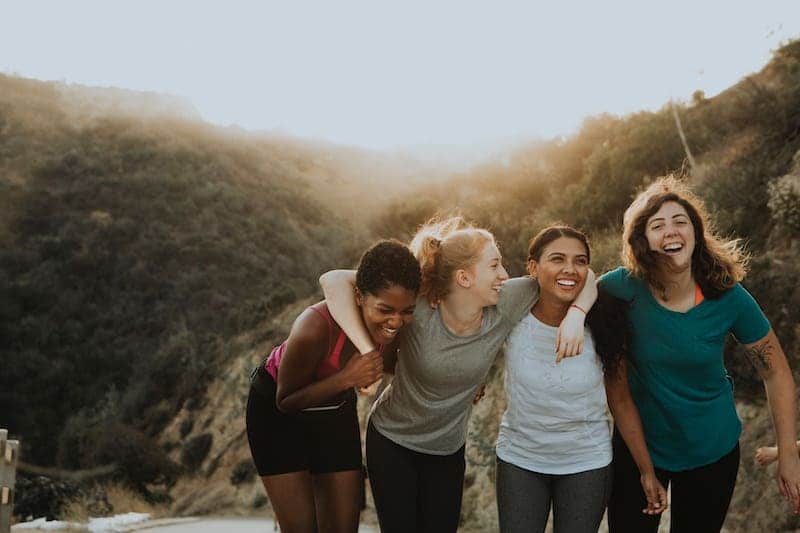 A group of young women smiling and laughing emphasize that the common good in Catholic social teaching focuses on the human person.