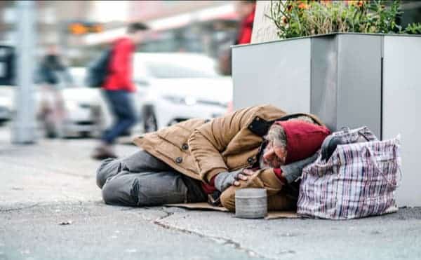 A homeless man sleeping on the street represents those who are materially poor, one group of those who need the preferential option for the poor
