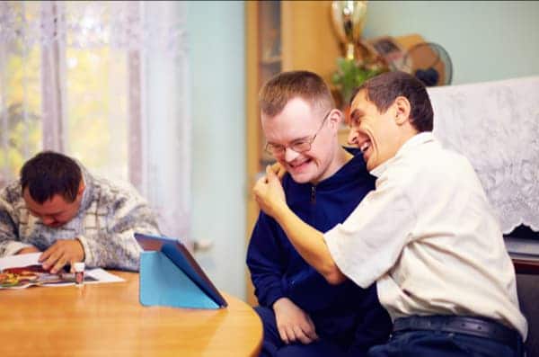 Two young adults with learning disabilities laugh together, calling to mind solidarity, the second of the principles of catholic social teaching