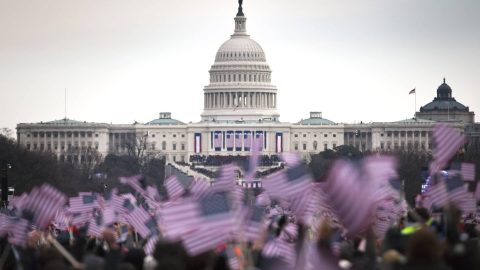 Waving flags at the capitol representing government, politics, democracy, and state responsibilities.