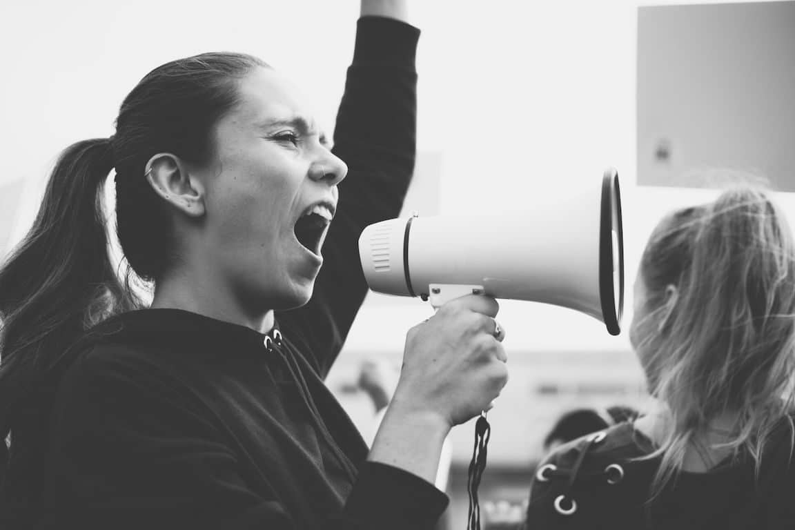 A woman shouts through a megaphone during a protest. Contemporary issues in our country need the Church's teachings.