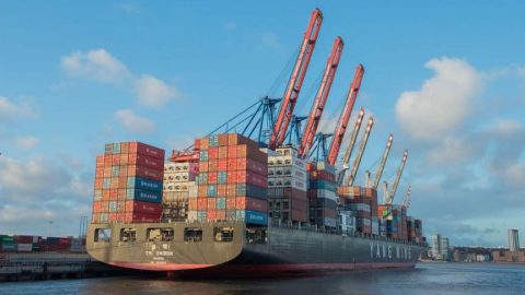 A cargo ship at port representing goods, economies, trade, and globalization.