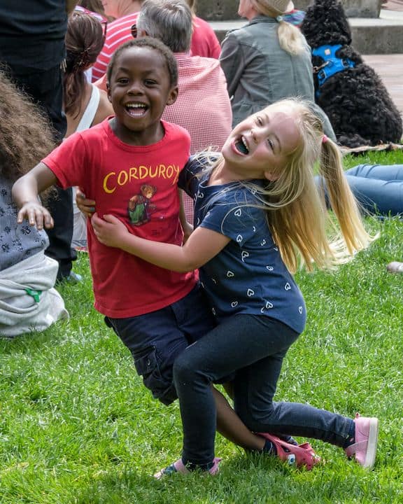 A white girl and a black boy play together in a field, showing how we can combat racism in the United States by recognizing human dignity