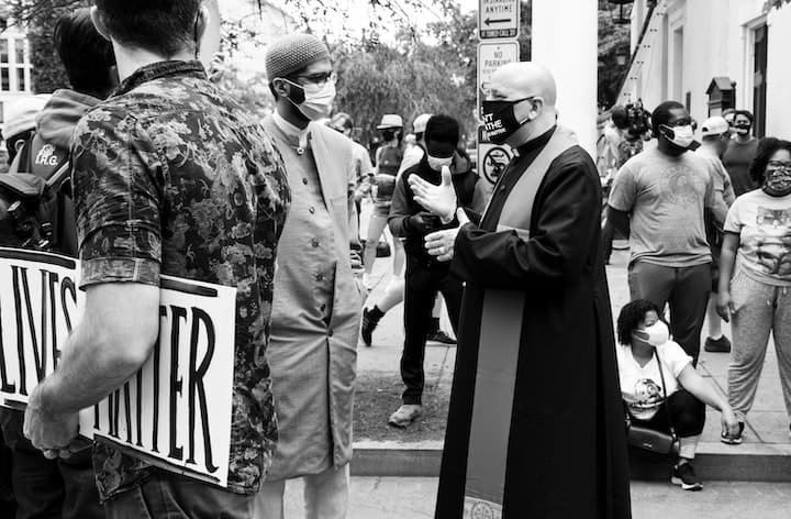 A Priest and a Muslim wearing face masks talk at a Black Lives Matter protest against racism in the United States