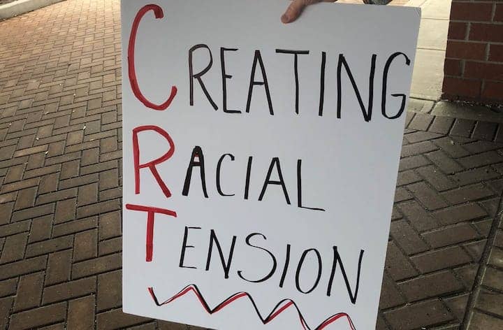 A sign labelled "Creating Racial Tension" criticizes Critical Race Theory as exacerbating racism in the United States