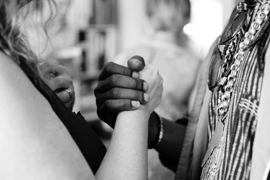 A black and a white woman clasp hands together, symbolizing how we can get beyond racism in the United States