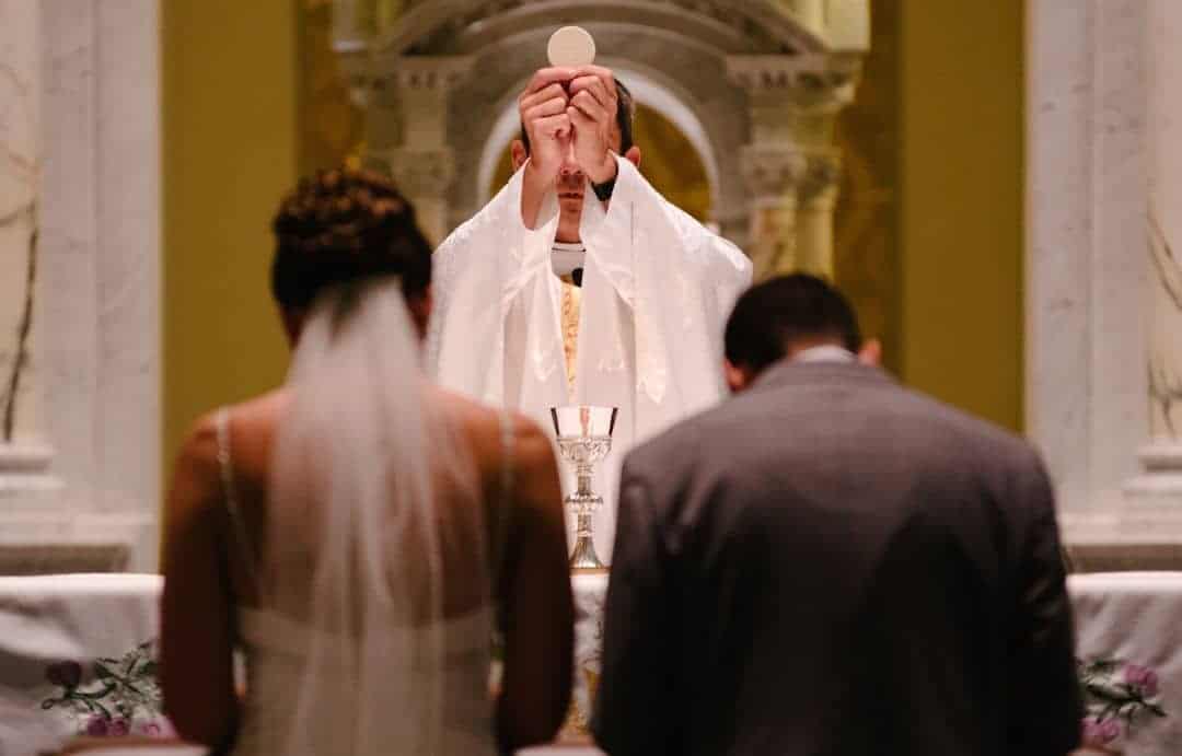 A Catholic wedding where new spouses prepare to receive the Eucharist. Marriage between a man and woman is fundamental.