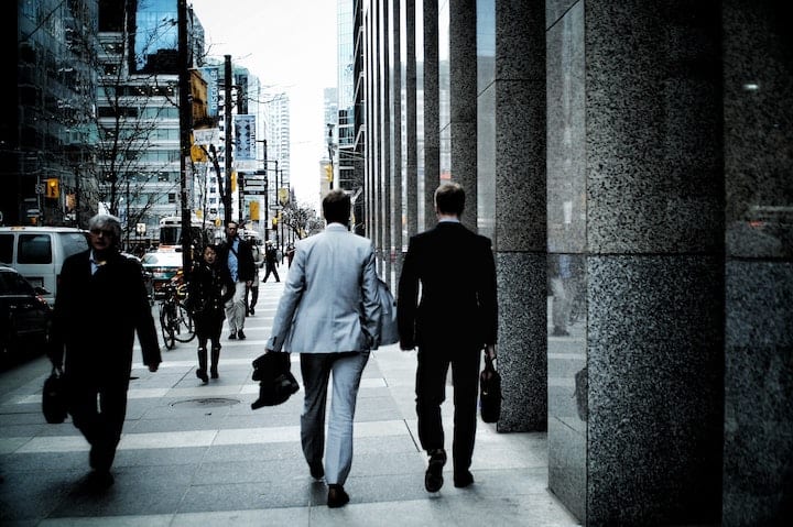 Two businessmen walking to work in a city downtown.